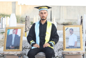 A young Yazidi man celebrates his graduation from university with pictures of his loved ones